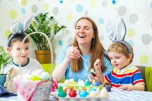 Happy Easter. A mother and her children painting Easter eggs photo