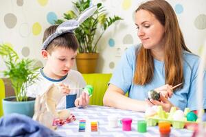 Happy Easter. A mother and her son painting Easter eggs photo