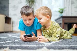 Two children watching smart phone, happy kids using smartphones together photo