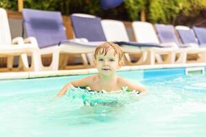 Child in swimming pool with inflatable circle enjoys summer vacation photo