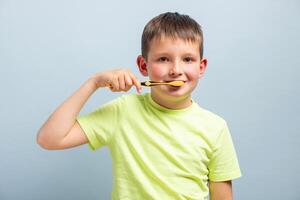 niño chico cepillado su dientes en azul antecedentes. el concepto de diario higiene foto