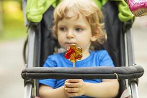 Toddler Holding Lollipop in Stroller photo