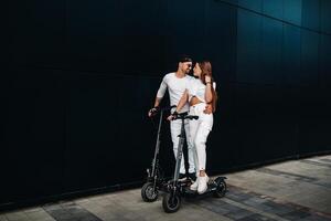 A girl and a guy are walking on electric scooters around the city, a couple in love on scooters. photo