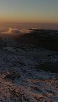 verticaal video van meer Aan montains en sneeuw Bij zonsondergang antenne visie