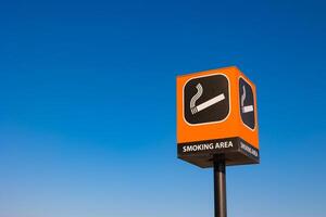 Smoking area signpost isolated on blue sky background photo