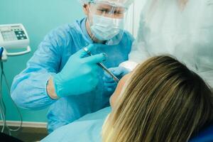a dentist in a protective mask colitis painkillers in the dental office with an assistant photo