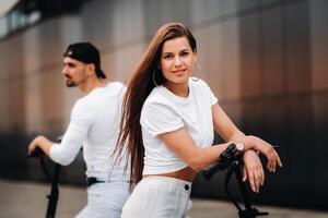 A girl and a guy are walking on electric scooters around the city, a couple in love on scooters. photo