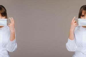 A girl doctor stands in a medical mask, isolated on a gray background. photo