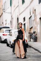 un hermosa elegante novia en un negro vestir camina mediante florencia, un modelo en un negro vestir en el antiguo ciudad de Italia foto