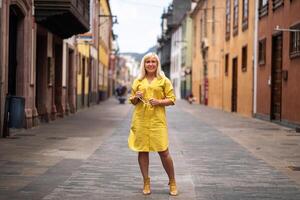a blonde woman in a yellow summer dress stands on the street of the Old town of La Laguna on the island of Tenerife.Spain, Canary Islands photo