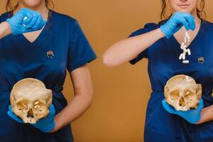 A pretty young doctor pours vitamin capsules into a human skull. The doctor pours pills on the background. photo