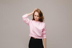 a girl with long hair on a gray background suffering from a headache holds her head with her hands. The girl puts her hands on her head, isolated against a gray background. The concept of problems photo