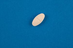 Diamond shape white pill isolated on blue background. photo