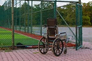 An empty wheelchair near the open gate of the soccer or football field. photo