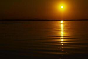 Red or orange sunset over the lake. Calm waves on the lake photo