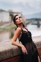 un hermosa elegante novia en un negro vestir camina mediante florencia, un modelo en un negro vestir en el antiguo ciudad de Italia foto