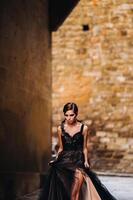 un hermosa elegante novia en un negro vestir camina mediante florencia, un modelo en un negro vestir en el antiguo ciudad de Italia foto