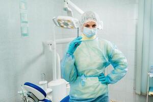 A masked dentist holds an injection syringe for a patient in the office photo