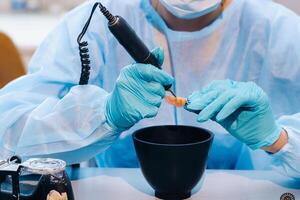 un enmascarado y enguantado dental técnico trabajos en un protésico diente en su laboratorio foto