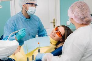 The patient smiles in the dentist's chair in a protective mask and instrument before treatment in the dental office photo