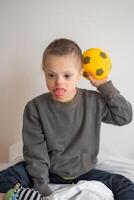 retrato de pequeño chico con abajo síndrome jugando con juguete en hogar dormitorio. alto calidad foto