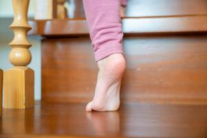 Closeup of little girl foot going up the stairs at home, child climbing stairs photo