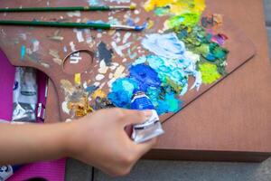 Palette with multi-colored paints and brushes, woman painting picture photo