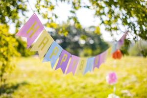 Text happy birthday on colorful paper flags in the park. photo