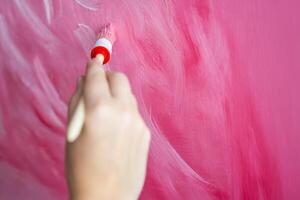 Close up view of woman artist hand with brush painting abstract pink picture on canvas. Art and creativity concept photo