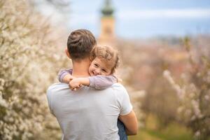 Father and daughter having a fun together under a blooming tree in spring park Petrin in Prague, Europe photo