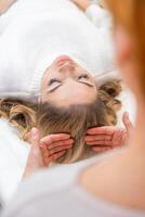Healer performing set of 32 points of access bars on woman head, stimulating positive change thoughts and emotions. Alternative medicine concept photo