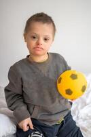 retrato de pequeño chico con abajo síndrome jugando con juguete en hogar dormitorio. alto calidad foto