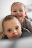 Small boy with down syndrome plays with his younger sister in home bedroom. High quality photo