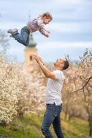 padre y hija teniendo un divertido juntos debajo un floreciente árbol en primavera parque petrin en praga, Europa foto