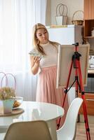 joven mujer artista con paleta y cepillo pintura resumen rosado imagen en lona a hogar cocina. Arte y creatividad concepto foto