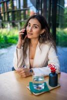 Young brunette business woman talking on the smart phone in street cafe of Prague photo
