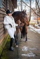 elegante rubio profesional hembra jockey en pie cerca caballo. amistad con caballo foto