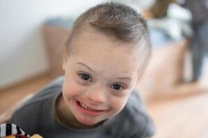 Portrait of small boy with down syndrome in home bedroom. High quality photo