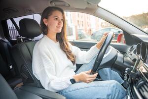 Side portrait of young caucasian woman driving car in the city photo