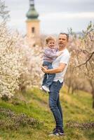 padre y hija teniendo un divertido juntos debajo un floreciente árbol en primavera parque petrin en praga, Europa foto
