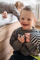 pequeño chico con abajo síndrome obras de teatro con su mas joven hermana en el cama en hogar dormitorio. alto calidad foto