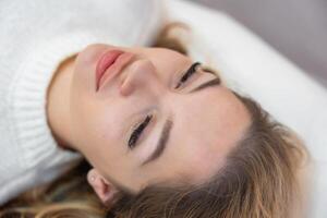 Close up face of beautiful woman lying on spa bed before procedure in cosmetology clinic photo