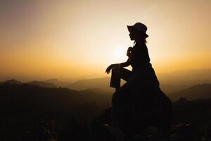 silueta de un mujer es Orando a Dios en el montaña. Orando manos con fe en religión y creencia en Dios en bendición antecedentes. poder de esperanza o amor y devoción. foto