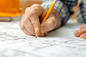 contractor drawing on blueprints with a pencil, creating a home improvement plan photo