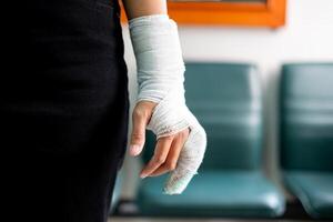 Woman's hand wrapped in white bandage from accident, injury, accident insurance, soft splint on finger, copy space photo