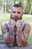 portrait of bearded man with elbows on the table in the park photo