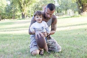 tattooed father have fun with his son in the park with rugby ball photo