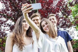 grupo de joven amigos tomar un selfie abrazado juntos foto