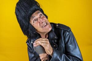 Funny portrait of mature rocker. An old singer dressed in rockabilly style in action photo