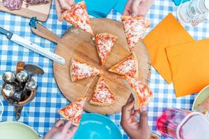 group of friends eating pizza. Top view of four hands taking pizza slices photo